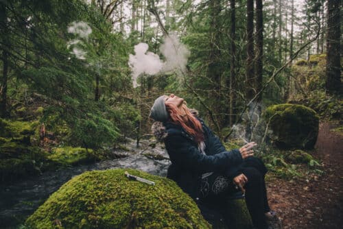 Woman alone in nature enjoying the quiet and smoking marijuana